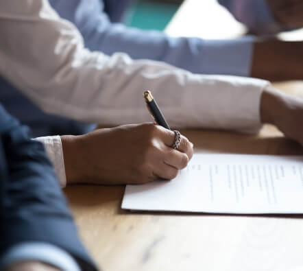 a close up of several people at a table, one of which is writing on a notepad